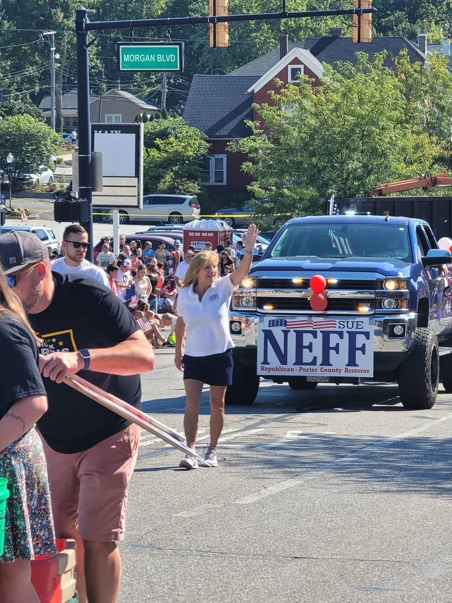 Sue waving to the crowd in front of a truck with a Neff sign during a parade