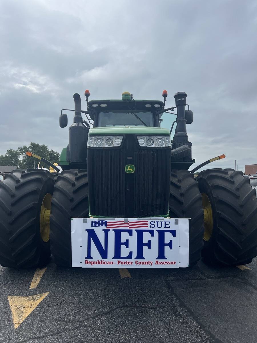 A large green tractor with a Sue Neff sign on the front